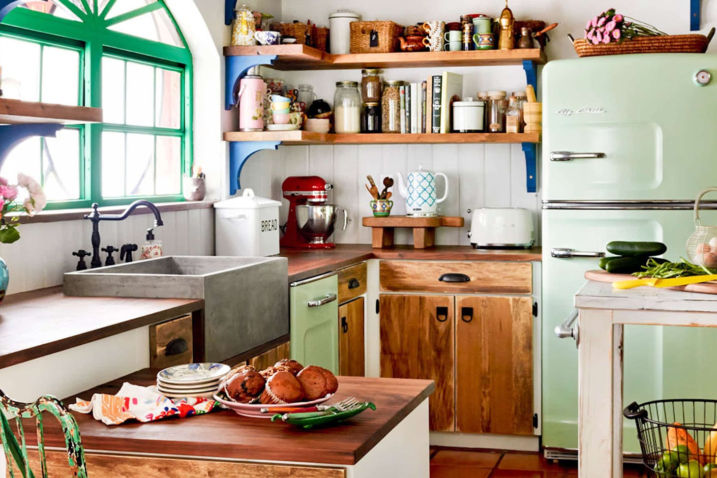 A gorgeous kitchen with vibrant pops of colour, greenery and stacked wooden shelving.